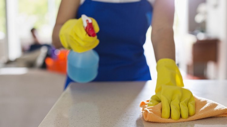 Professional house cleaner sanitizing a countertop in a Monument home.